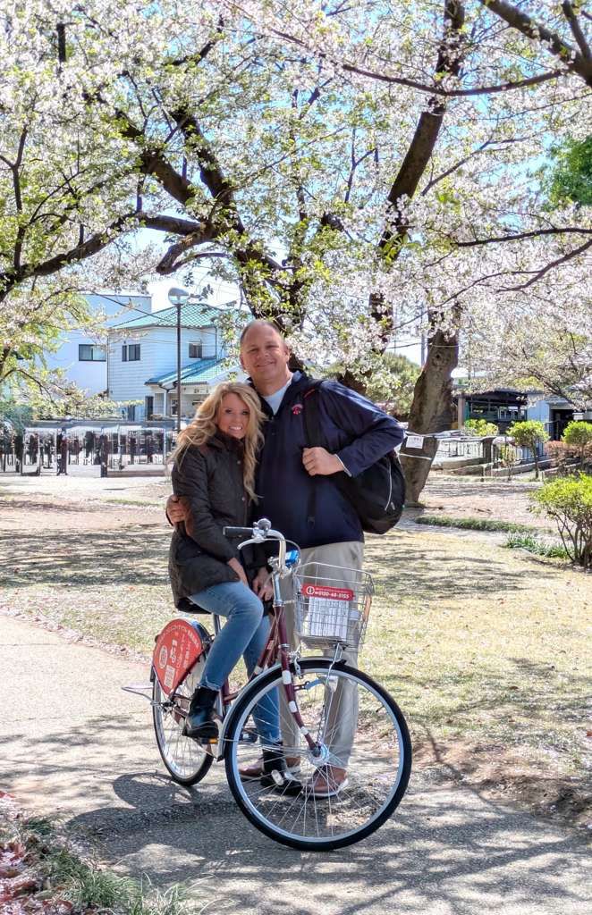 Angela Hughes enjoying a bike ride beneath cherry blossoms in Tokyo, Japan during sakura season. Luxury travel expert and CEO of Trips & Ships Luxury Travel explores Japan’s iconic spring scenery and cultural experiences.