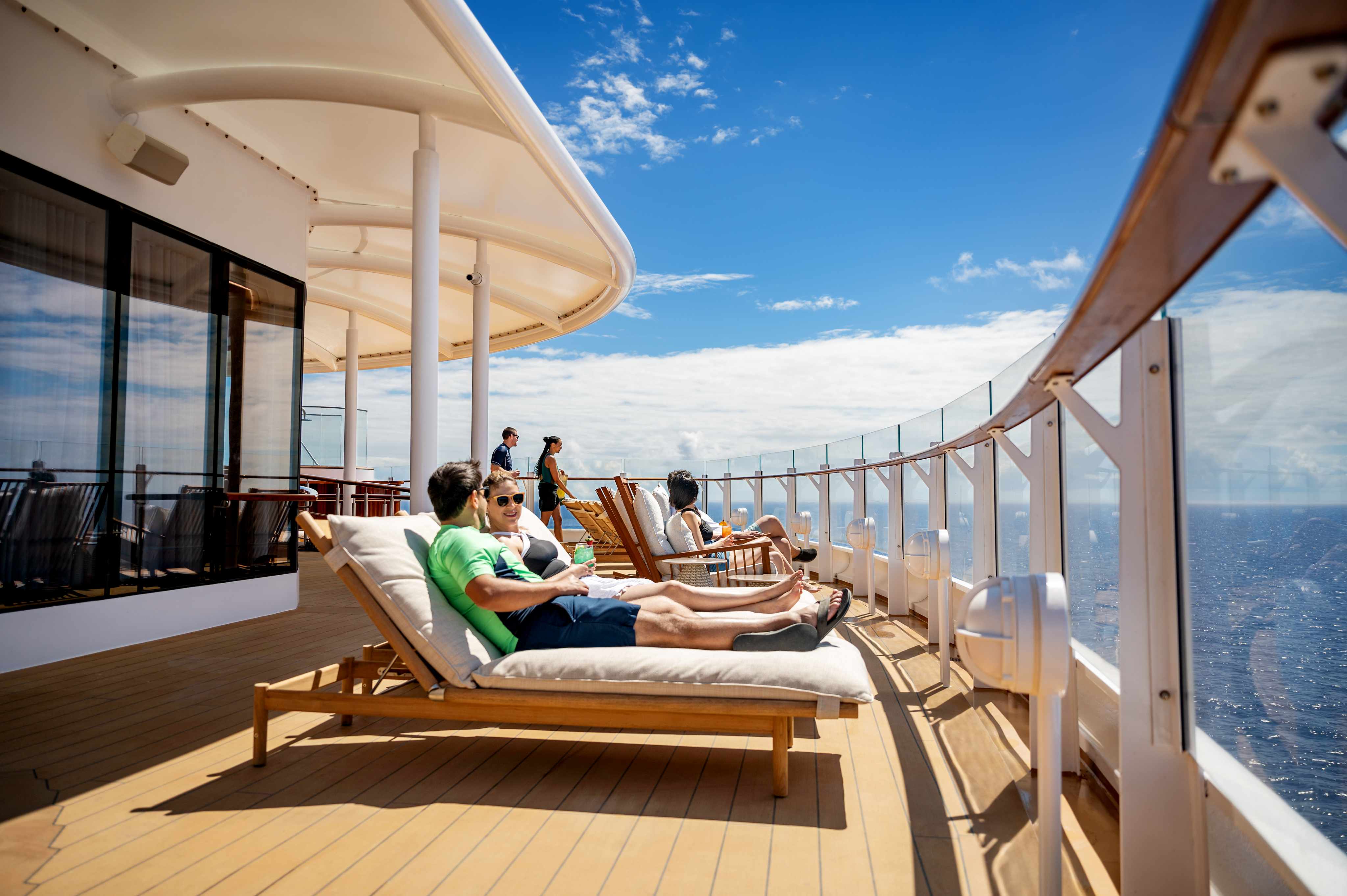 Guests relaxing on a luxury cruise ship veranda overlooking the ocean
